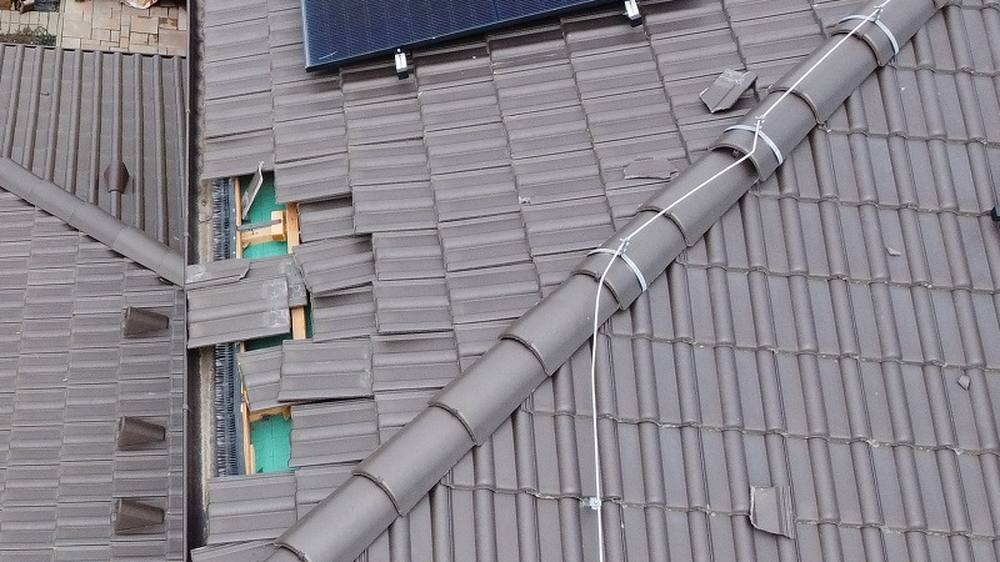 Poškodená škridlová strecha z dronu: chýbajúce škridly s odhalenou poistnou fóliou a vytočená hrebeňová škridla s príchytkou bleskozvodu